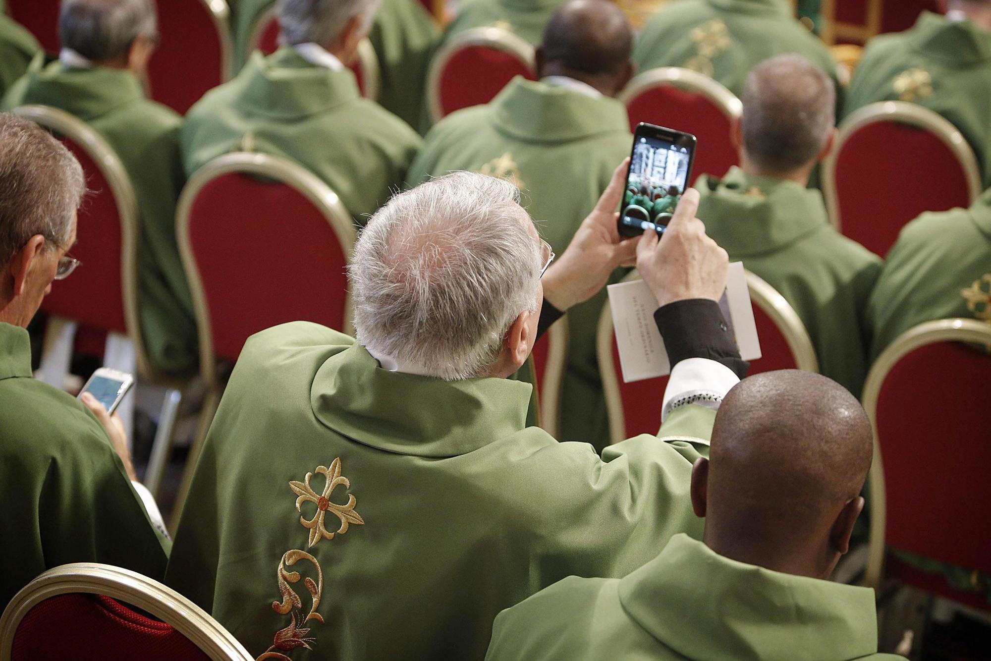 Un obispo toma una foto durante la misa de apertura de la XVI Reunión Ordinaria del Sínodo de los Obispos.