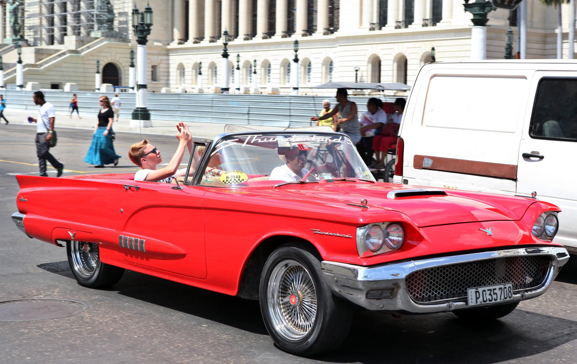 Turistas toman fotos mientras pasea en un auto clásico en La Habana en julio del 2015.