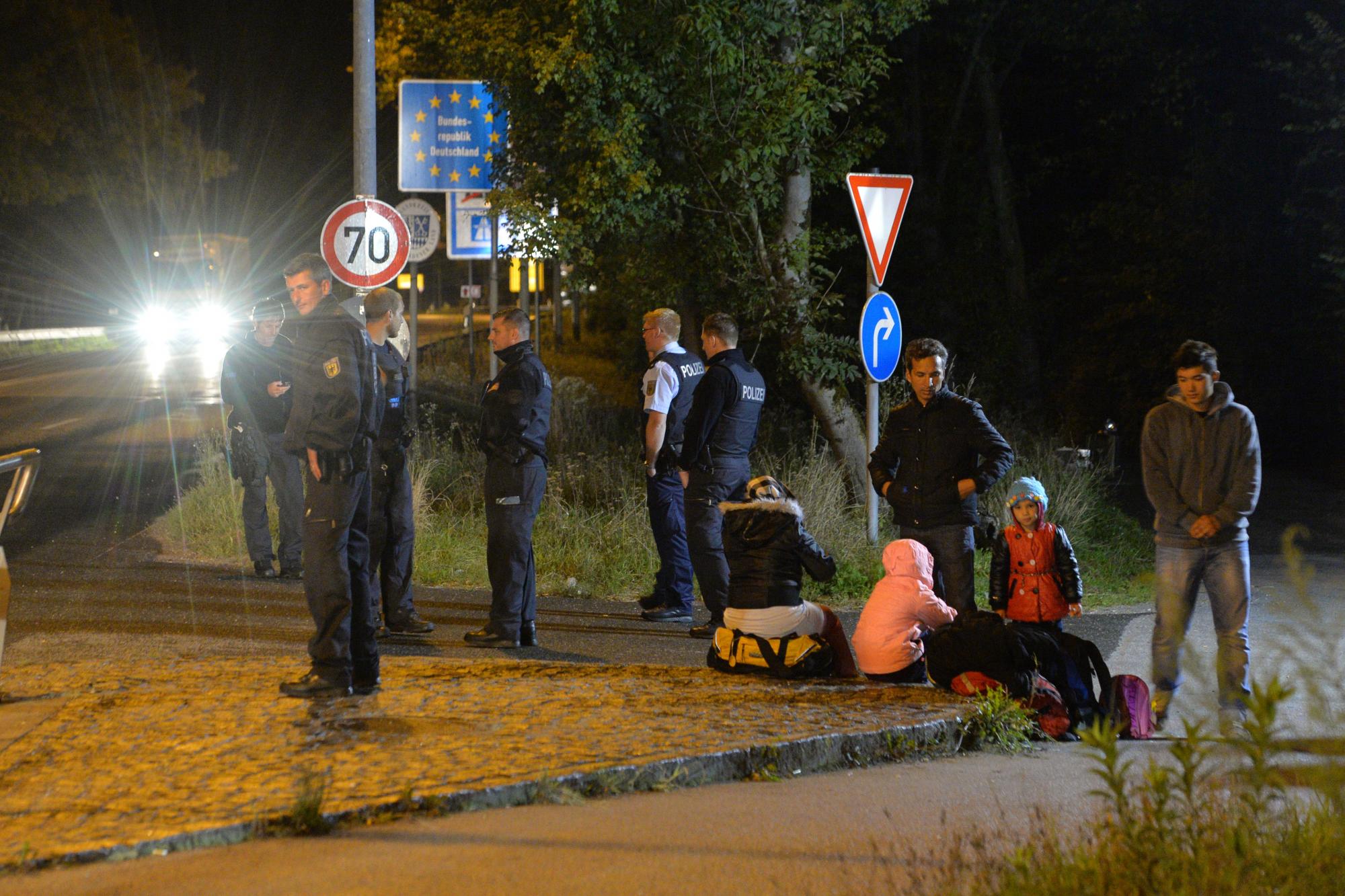 La policía federal alemana aguarda junto a varios refugiados que esperan en la frontera entre Freilassing, Alemania, y Salzburgo, Austria, el lunes 14 de septiembre de 2015. 