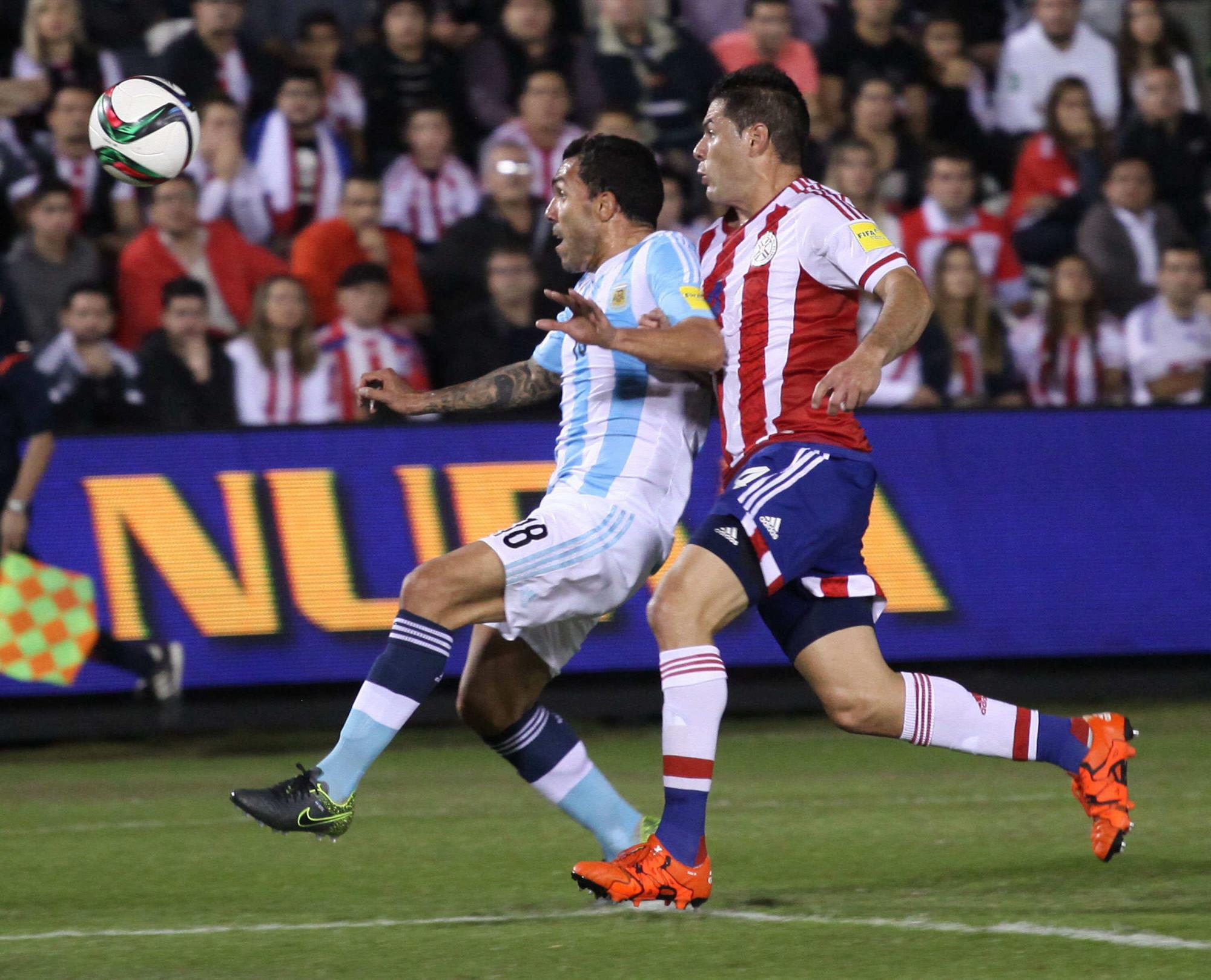 El jugador de la selección de Argentina, Carlos Teves, disputa el balón con Pablo Aguilar (d), de Paraguay. 