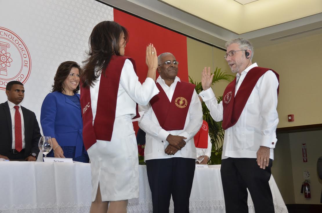 Paul Krugman durante el juramento. A la izquierda, Claudia de los Santos, presidenta de la Junta de Regentes, y Rolando Guzmán, rector, de INTEC. 