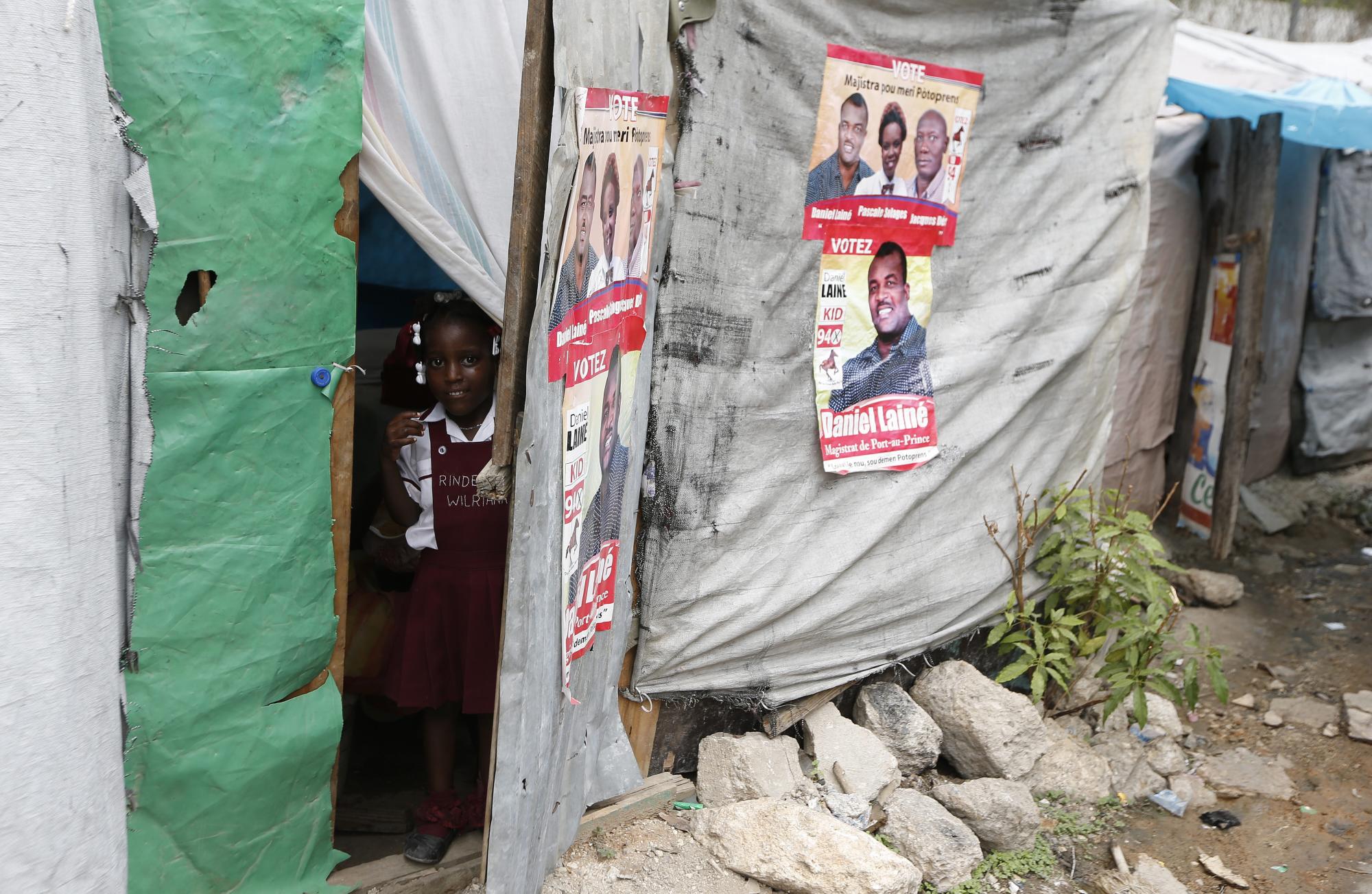 Una estudiante se asoma por la entrada de su casa en el barrio Bel Air con algunos carteles de publicidad política. 