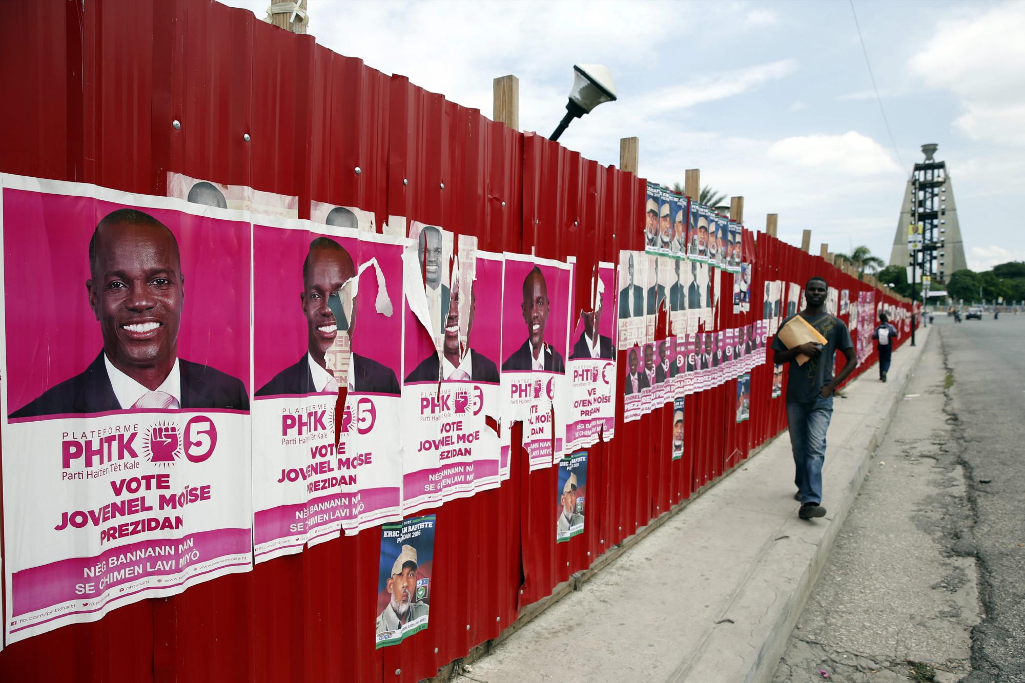 Un hombre camina junto a varios carteles de campaña política en Champ Mars. 