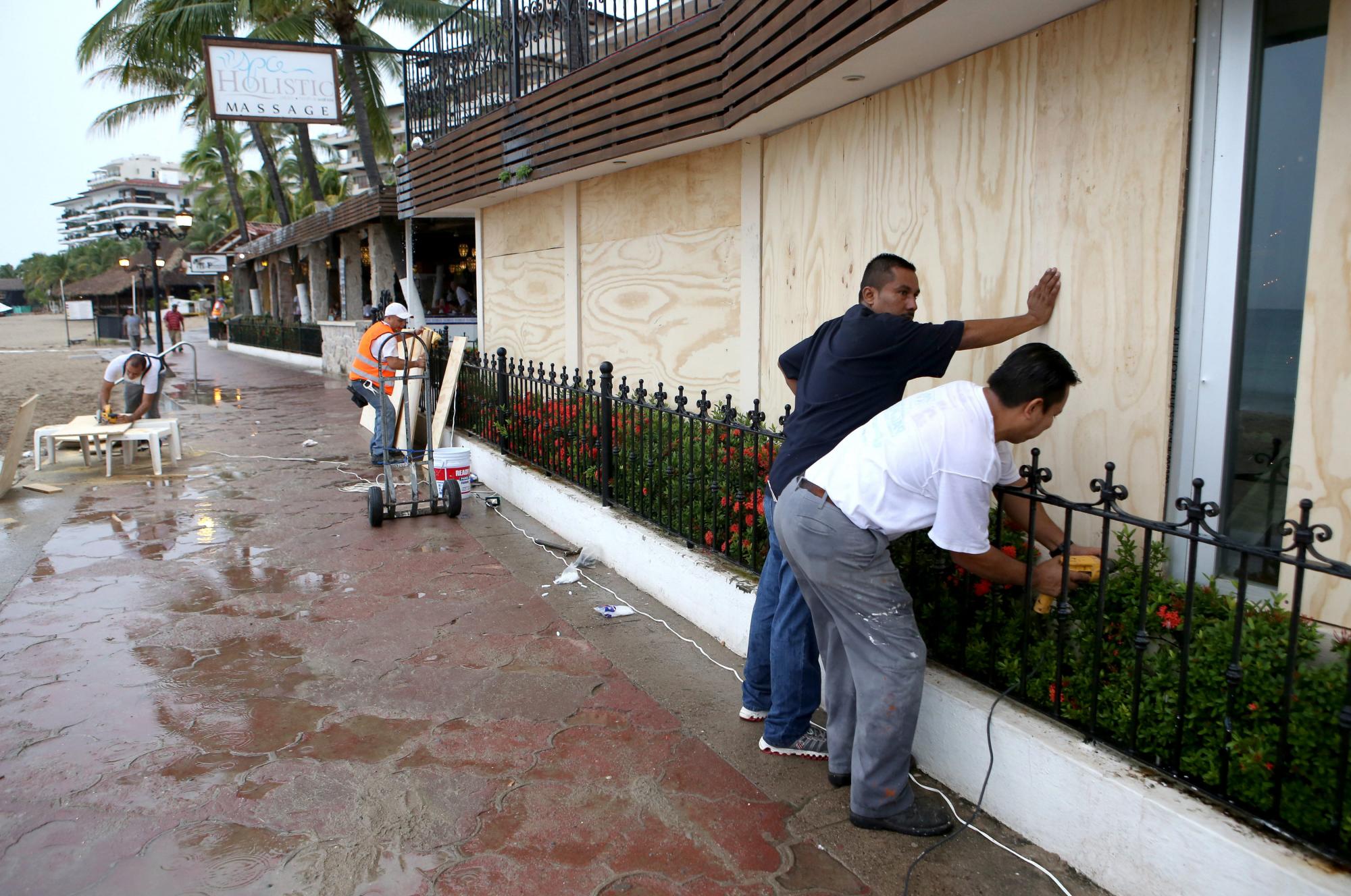 PUERTO VALLARTA. Habitantes de la zona turística de Puerto Vallarta en el estado de Jalisco (México) protegen sus casas y comercios hoy, viernes 23 de octubre de 2015, ante la inminente llegada del huracán Patricia. El huracán Patricia, que anoche llegó a la categoría 5, la máxima en la escala de Saffir-Simpson, continúa fortaleciéndose y esta madrugada alcanzó récords de vientos y presión para el Pacífico noreste, informó hoy el Servicio Meteorológico Nacional (SMN) de México. La velocidad de sus vientos sostenidos es de 325 kilómetros por hora y alcanza rachas de hasta 400. Miles de habitantes y turistas de las costas de los estados de Jalisco, Colima y Nayarit están siendo evacuados.