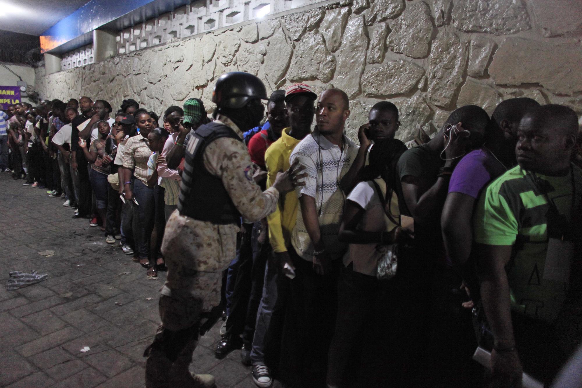 Un policía nacional empuja a un votante para que se forme en una fila frente a una casilla electoral en Petion-Ville, un suburbio de Puerto Príncipe, Haití, el domingo 25 de octubre de 2015. (Foto AP/Ricardo Arduengo)