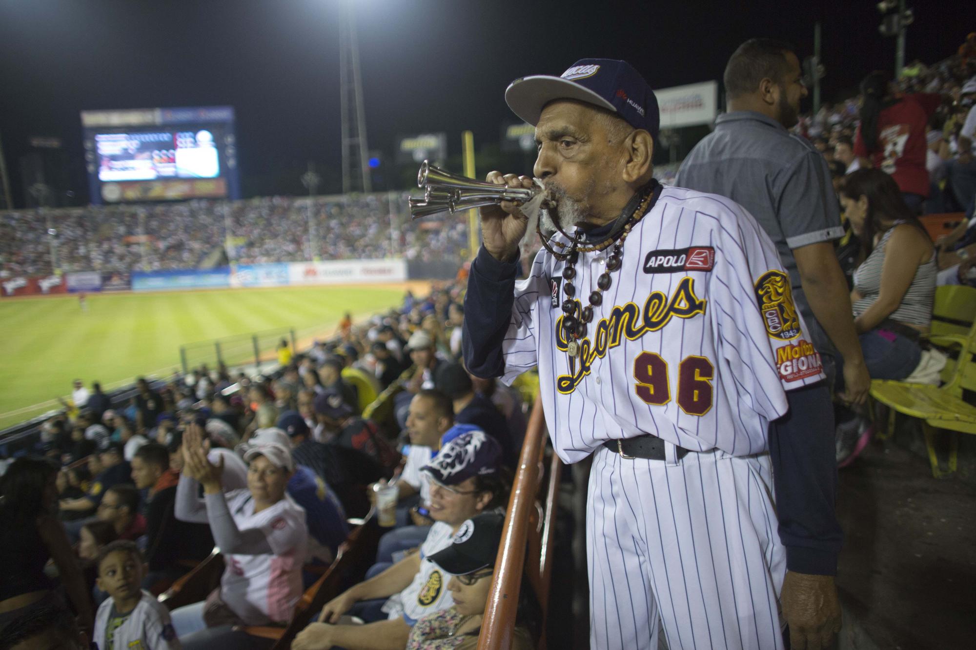 Jesús Lezama, de 96 años de edad y seguidor de los Leones de Caracas, toca una corneta durante el duelo contra los Navegantes del Magallanes en Caracas, Venezuela.