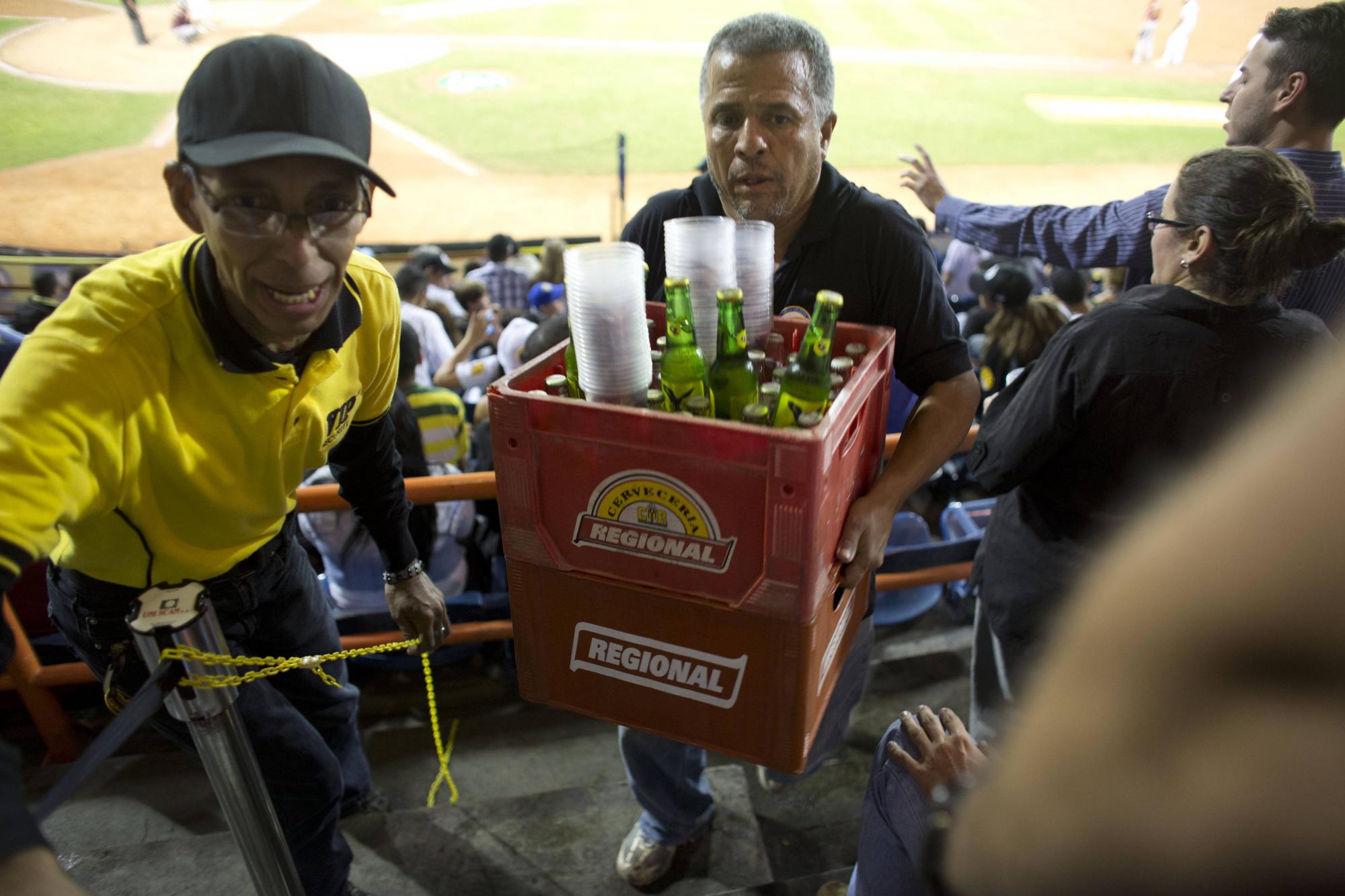 Un vendedor carga envases de cerveza durante un juego de béisbol entre los Leones de Caracas y los Navegantes de Magallanes en Caracas, Venezuela. 