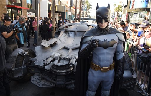 Un disfraz de Batman posa junta al último batimóvil construido en el Hollywood Boulevard.