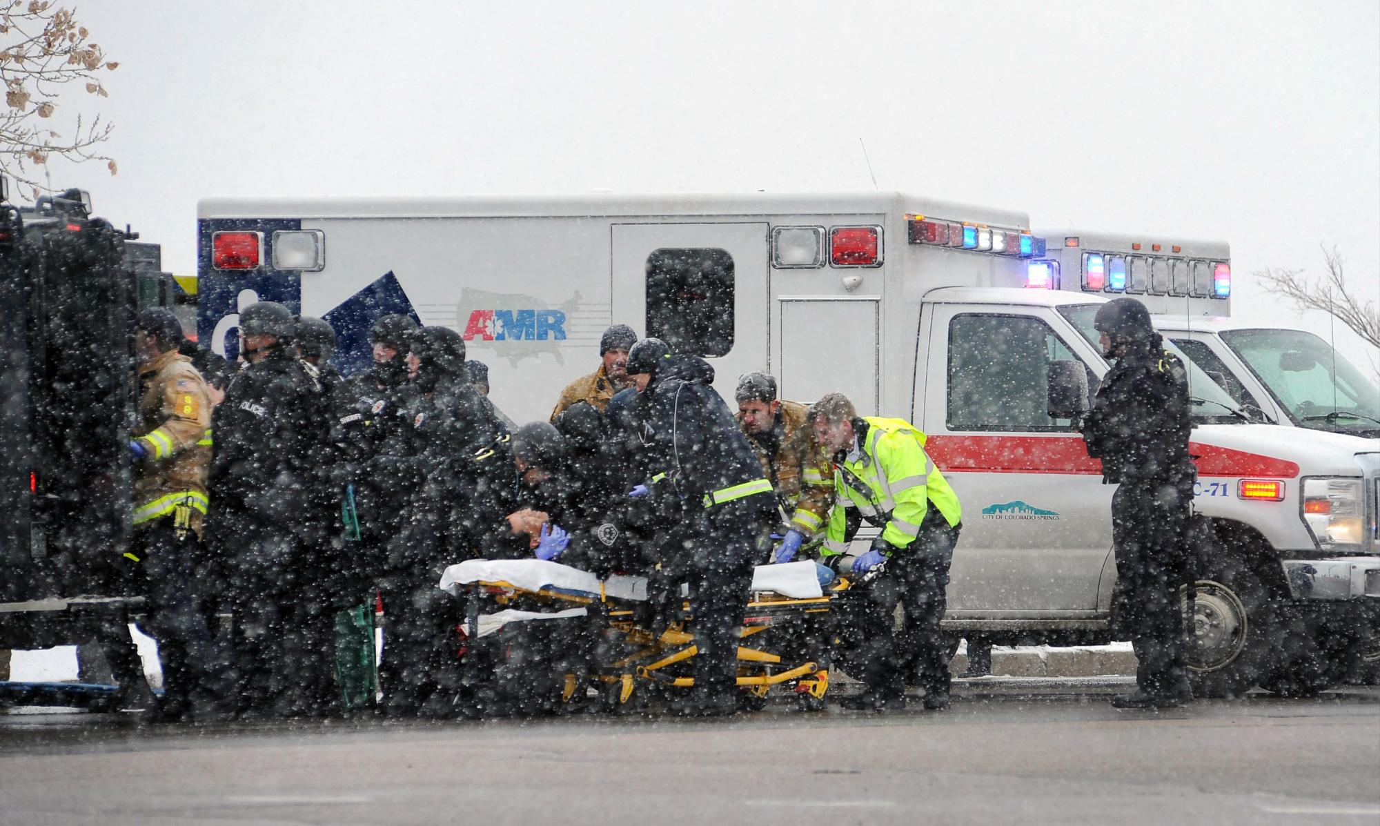 Bajo una nevada ligera, personal de emergencia lleva a un agente herido hasta una ambulancia durante un tiroteo cerca de una clínica de Planned Parenthood en Colorado Springs, Colorado, el viernes 27 de noviembre de 2015. Según las autoridades, varias personas resultaron heridas en el tiroteo.