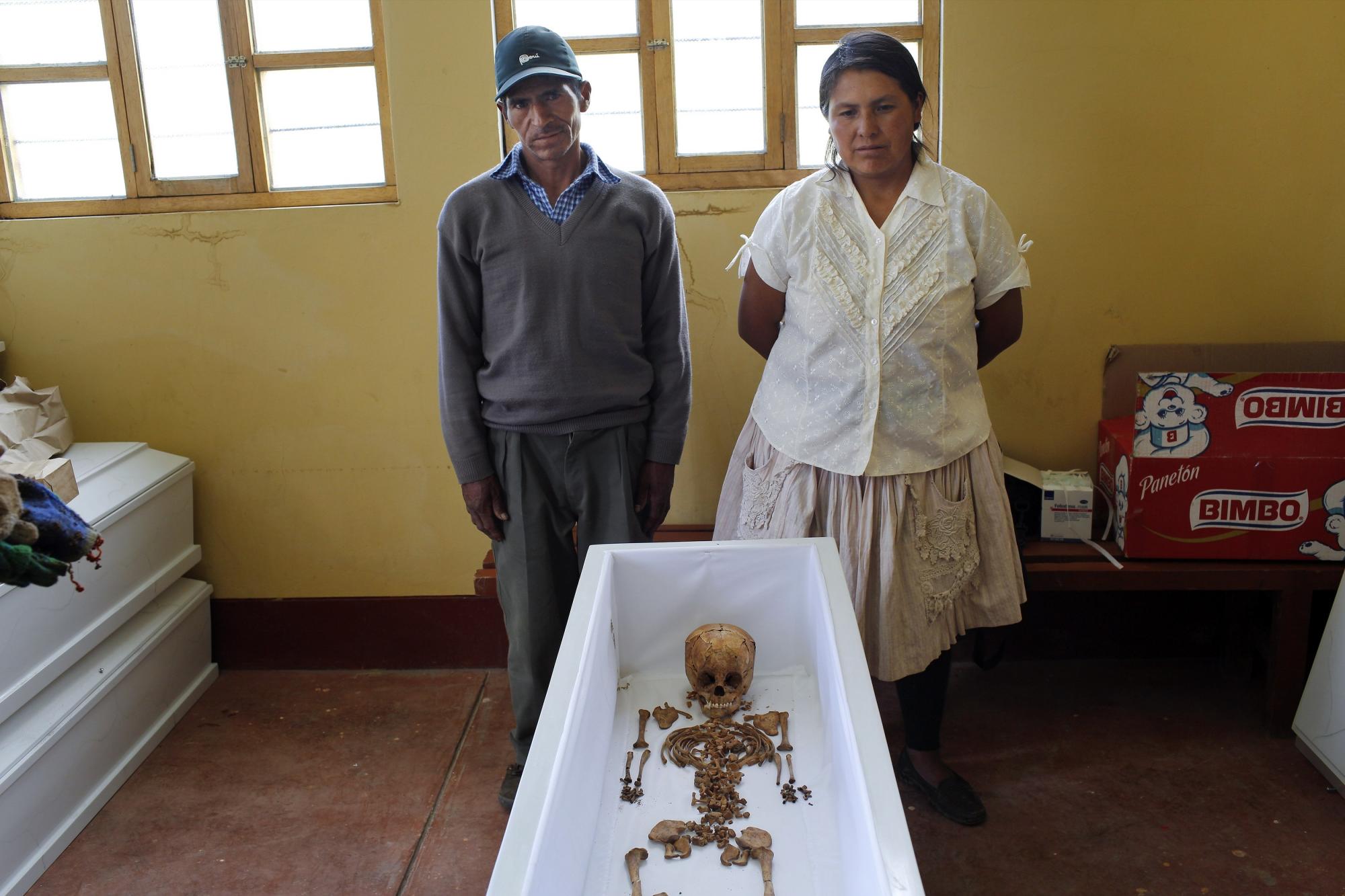 En esta imagen, tomada el 25 de noviembre de 2015, Julián Quispe Huallpa y su esposa Lidia Quispe, posan para una fotografía junto a los restos exhumados de su sobrina de 3 años, Necisa Curo Quispe, luego de que antropólofos forenses colocasen sus restos óseos en el ataúd, en Valle Esmeralda de Huayao, Perú. Necisa Curo Quispe fue asesinada en 1992, cuando miembros de Sendero Luminoso rodearon la localidad y y mataron a ancianos, hombres, mujeres y niños.