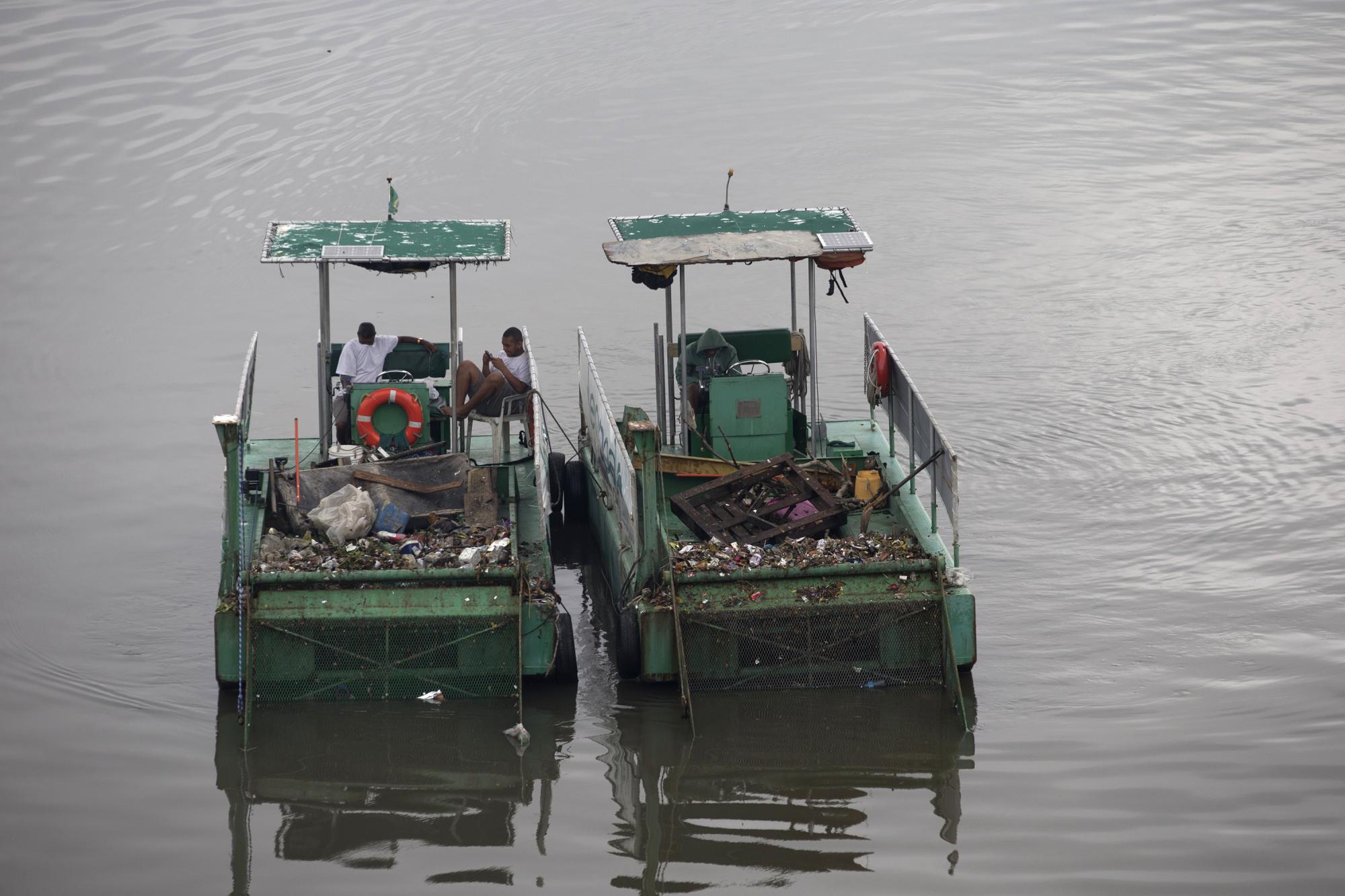 En esta imagen, tomada el 5 de noviembre de 2015, operarios descansan a bordo de dos eco-barcos, o embarcaciones para recolectar basura, en un canal en Río de Janeiro, Brasil. Los barcos son una parte fundamentar de los esfuerzos institucionales para limpiar la bahía de Guanabara, en Río, antes de que esta y otras vías de agua de otras ciudades acojan las pruebas de natación y remo de los Juegos Olímpicos de 2016.