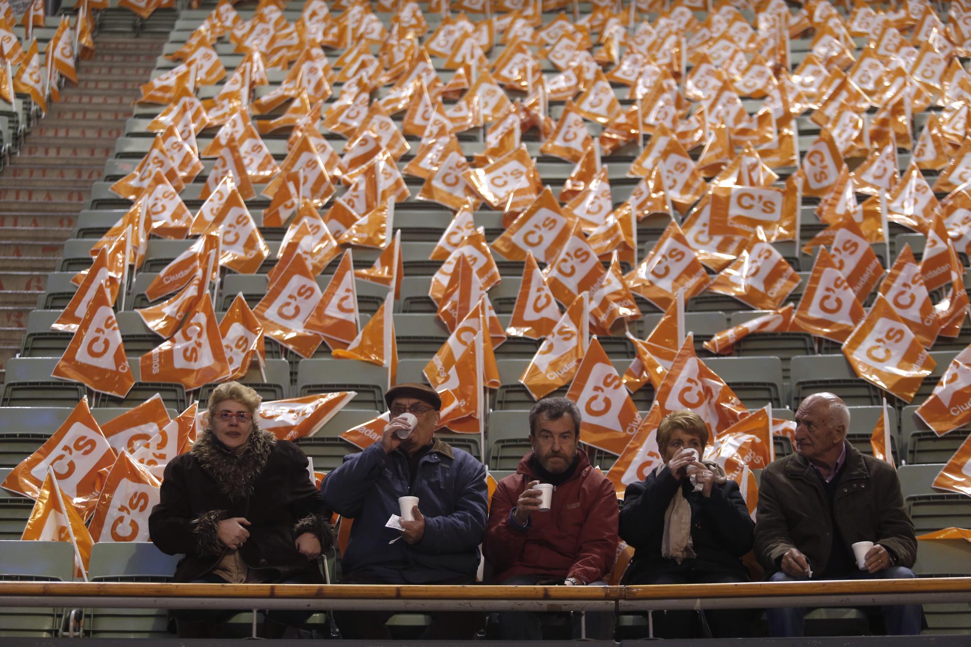 En esta imagen, tomada el 13 de diciembre de 2015, un grupo de personas bebe un chocolate caliente mientras espera el inicio de un acto electoral de Ciudadanos en Madrid, España. Las encuestas muestran que el Partido Popular del presidente Mariano Rajoy será el más votado, aunque no obtendría los apoyos necesarios para conservar la abrumadora mayoría que tiene en el Parlamento _ lo que supondría que tendría que asociarse con otra formación, probablemente Ciudadanos. Otra posibilidad podría ser una coalición entre los socialistas y Podemos. 