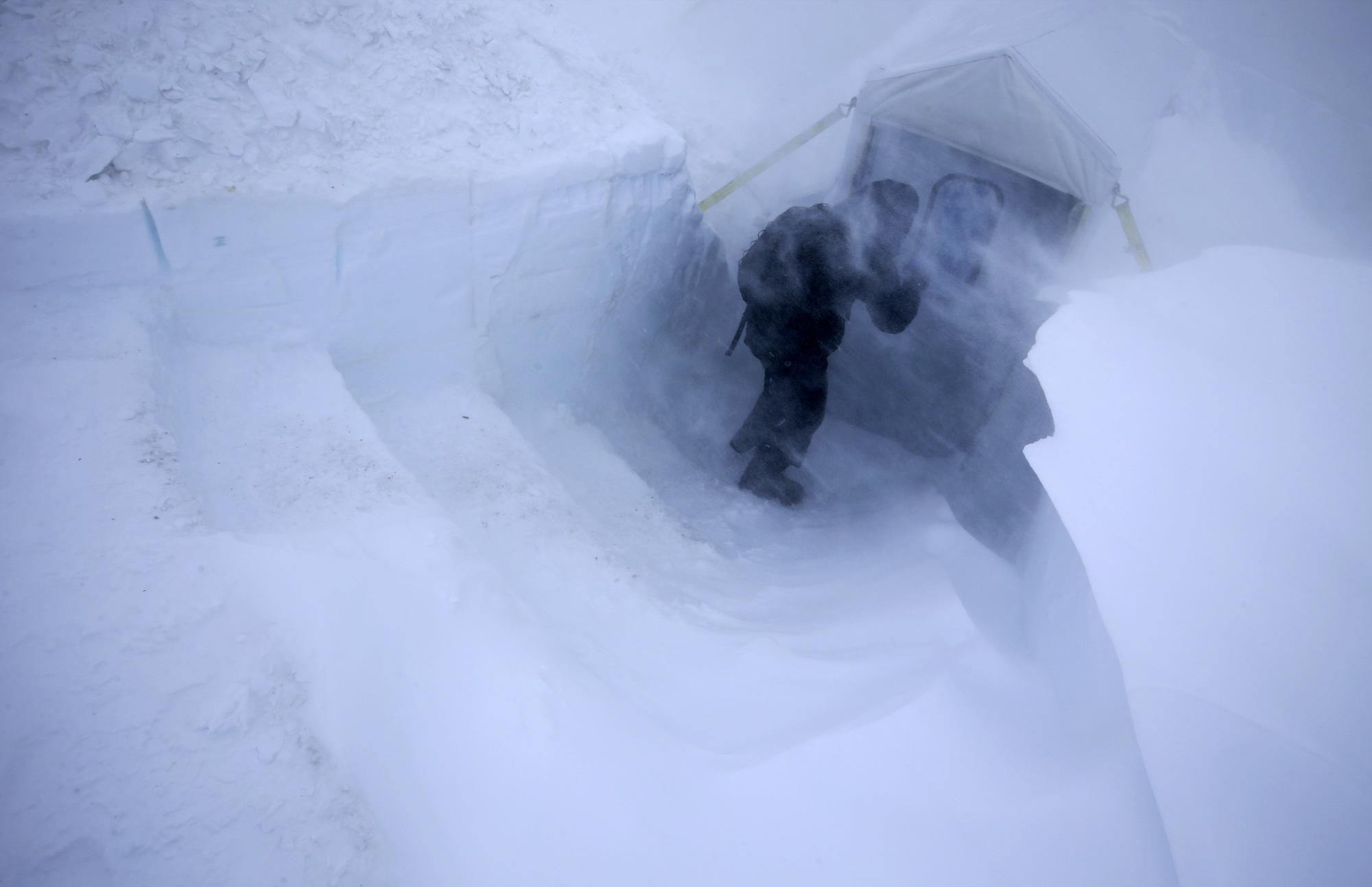 Fotografía del 29 de noviembre de 2015, que muestra a un hombre buscando refugio en un carpa semienterrada en la nieve durante una ventisca.