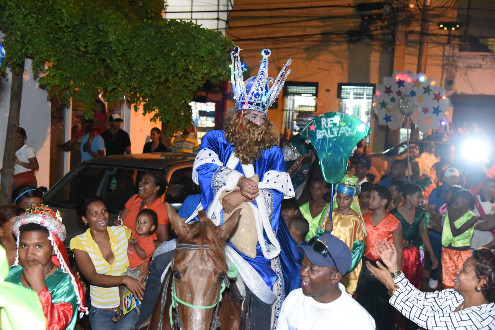 El “Rey Baltasar” repartiendo dulces a los presentes durante su trayecto.