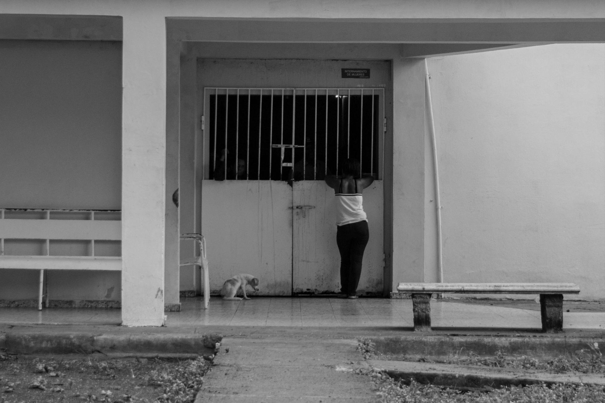 Una mujer y un perro frente al pabellón temporal de mujeres, el antiguo está en remodelación.