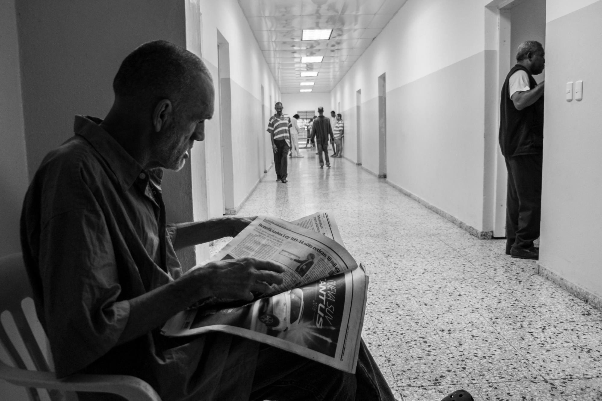 Rafael lee el periódico bajo el dintel del pabellón que lo confina.