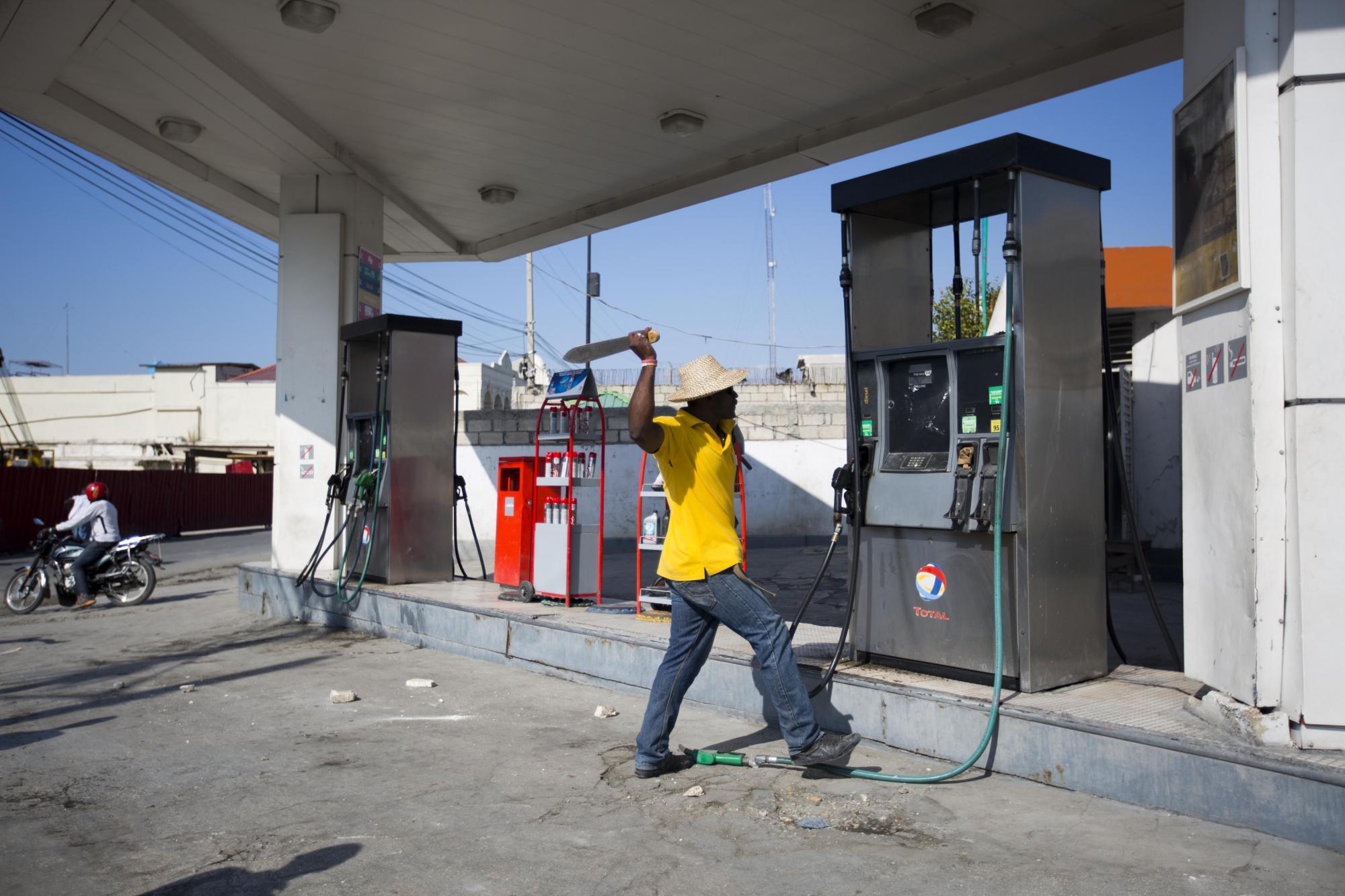 Un manifestante golpea con un machete una bomba de gasolina durante una protesta.