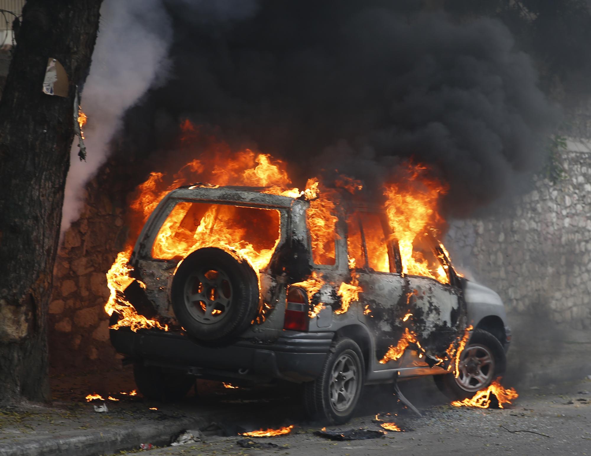 Fotografía de un vehículo incendiado tras una marcha opositora hoy, viernes 22 de enero de 2016, en Puerto Príncipe.