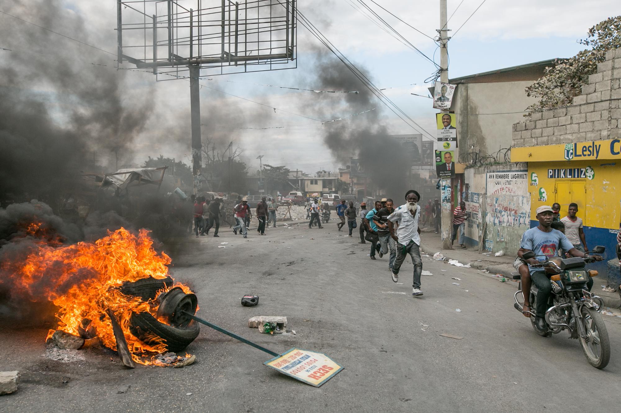 Manifestantes encienden neumáticos en camino de una oficina de elecciones hoy, viernes 22 de enero de 2016, en Puerto Príncipe.