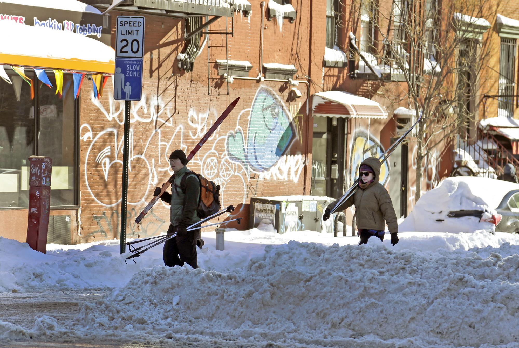 Dos personas cargan equipos de esquí por las calles cubiertas de nieve del Lower East Side, New York.
