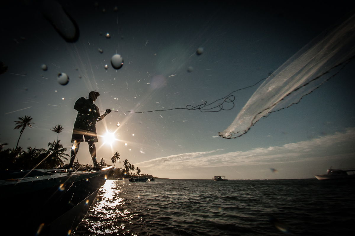 Un pescador lanza su red al amanecer en la playa de Mano Juan