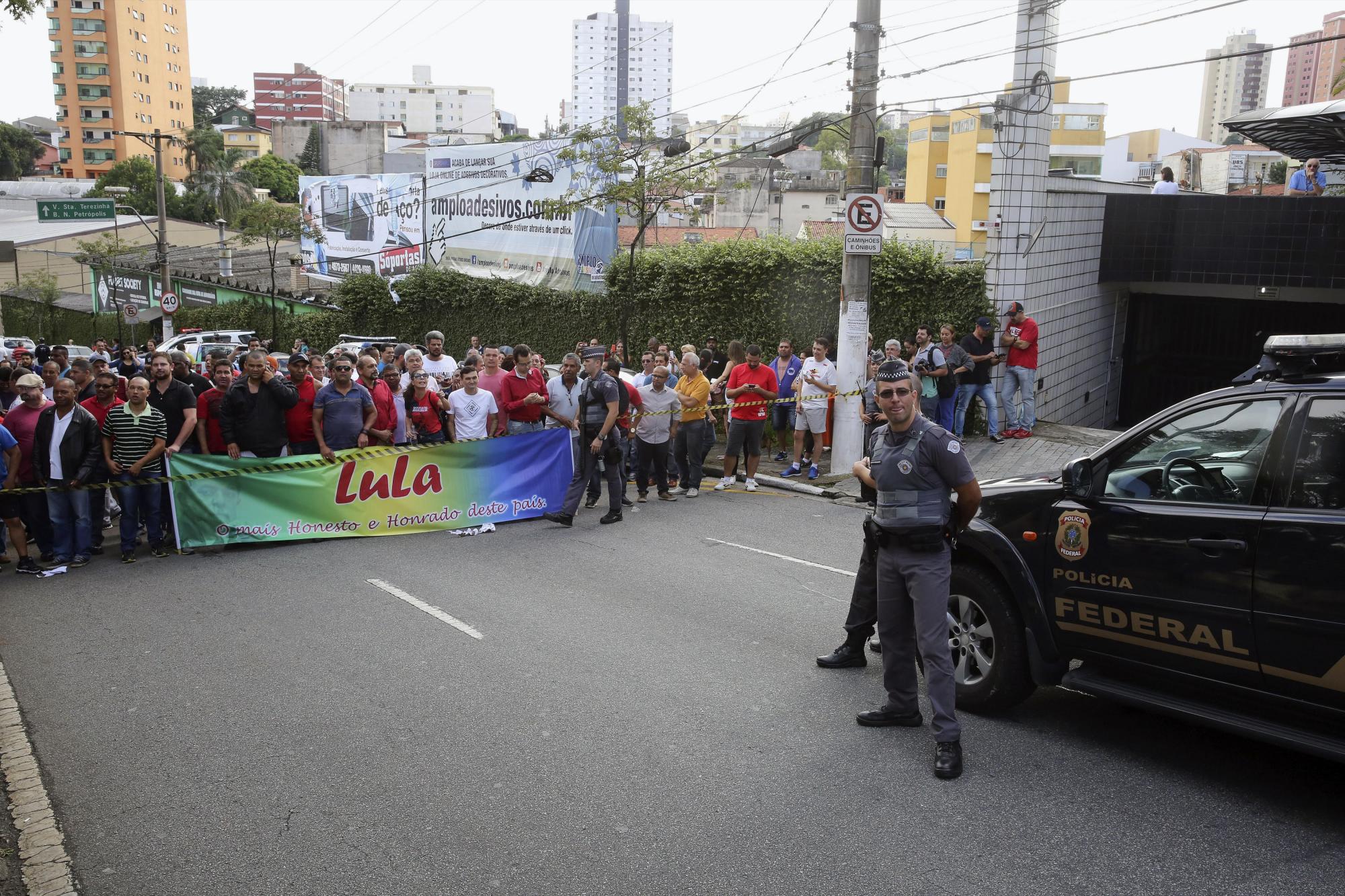 Agentes de Policía y ciudadanos con pancartas ante la residencia de Lula en la ciudad de Sao Bernardo do Campo, en la periferia de Sao Paulo.  