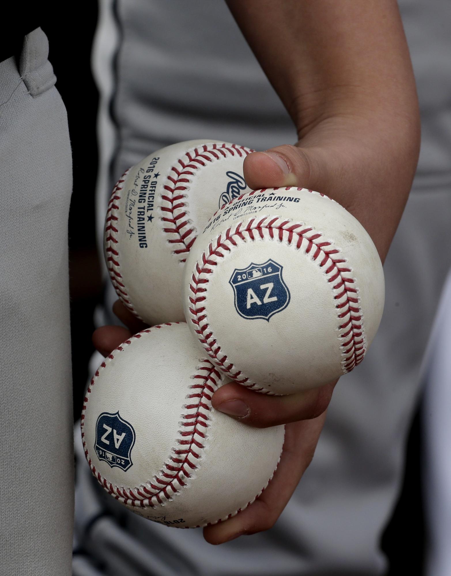 Un carga bate sostiene varias pelotas antes de un encuentro entre Marineros y Diamantinas en Peoria, Arizona.