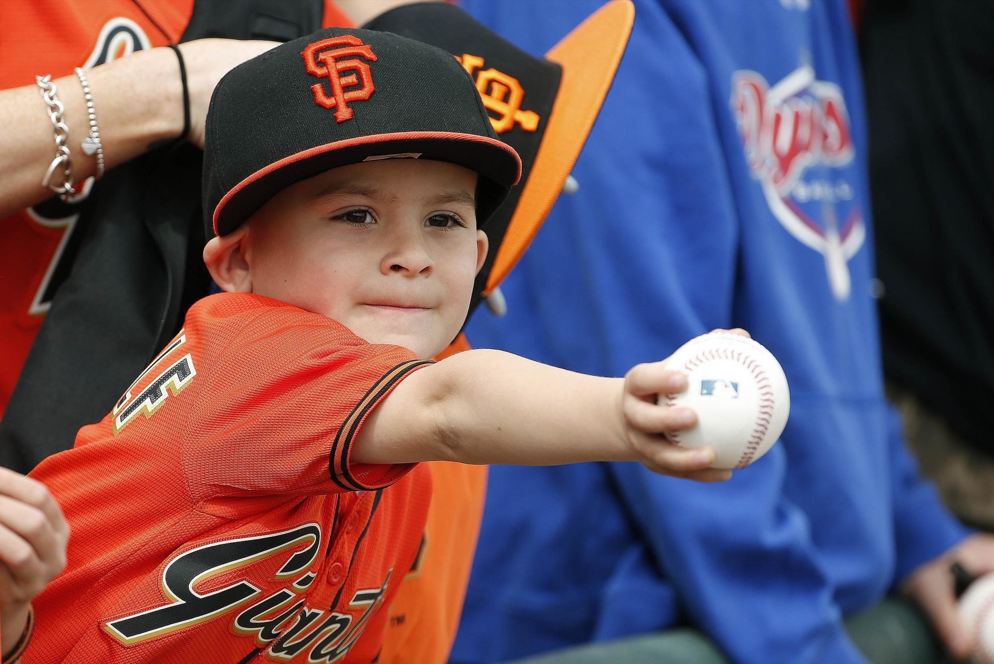 Un niño, fanático de los Gigantes de San Francisco, intenta tomar un autógrafo antes de un partido de su equipo contra los Vigilantes de Texas en Surprise, Arizona