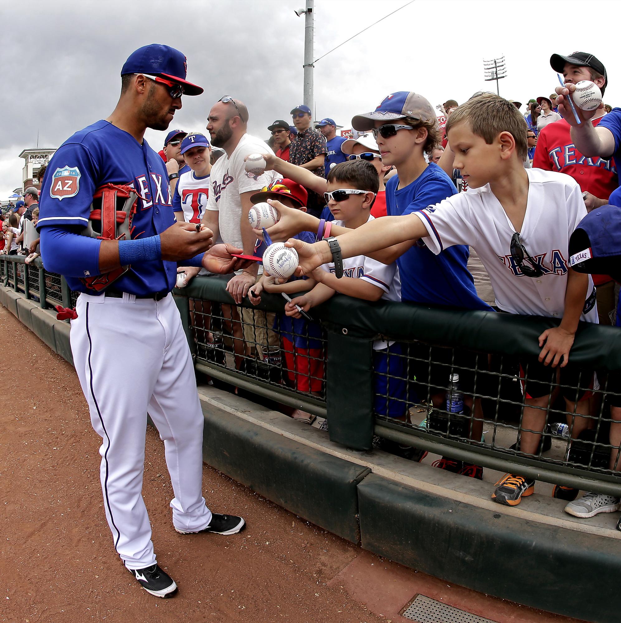 Ian Desmond tuvo una jornada intensa con la firma de autógrafos. Aquí sigue complaciendo a los fanáticos, en especial a los niños, antes del partido de Texas y Seattle. 