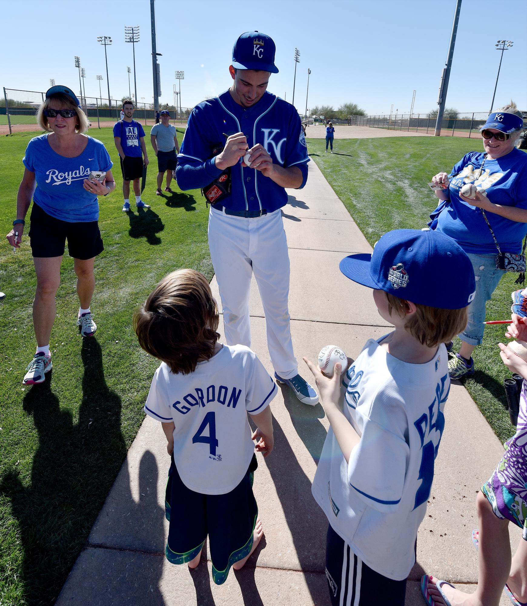 El lanzador de los Reales de Kansas City, Kyle Zimmer se detiene a firmar autógrafos a niños en Surprise, Arizona.