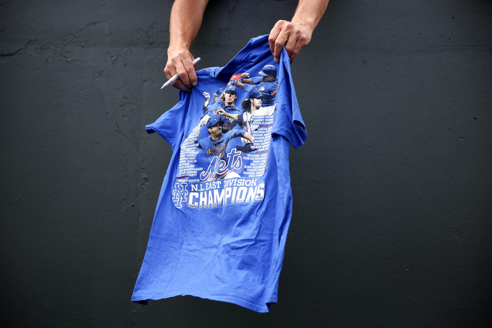 Durante el partido entre Mets y San Luis, un fanático pone su camiseta cerca del dugout con el fin de obtener un autógrafo. 