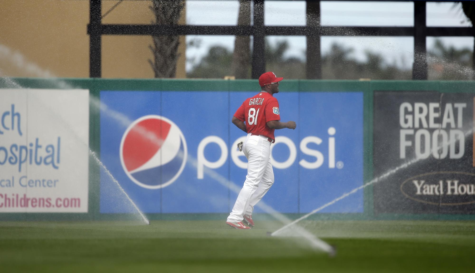 El puertorriqueño Anthony García, de los Cardenales de San Luis, trota, mientras fue sorprendido por los aspersores durante el sexto episodio de un partido de exhibición ante los Mets de Nueva York el pasado 7 de junio en Jupiter, Florida.