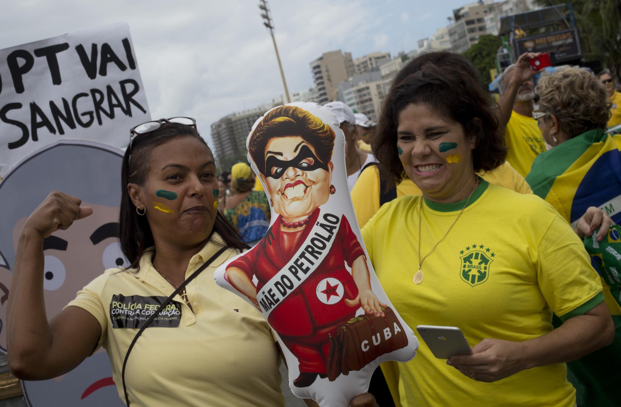 Manifestantes hacen gestos para pretender que golpean una imagen de la presidenta de Brasil, Dilma Rousseff.