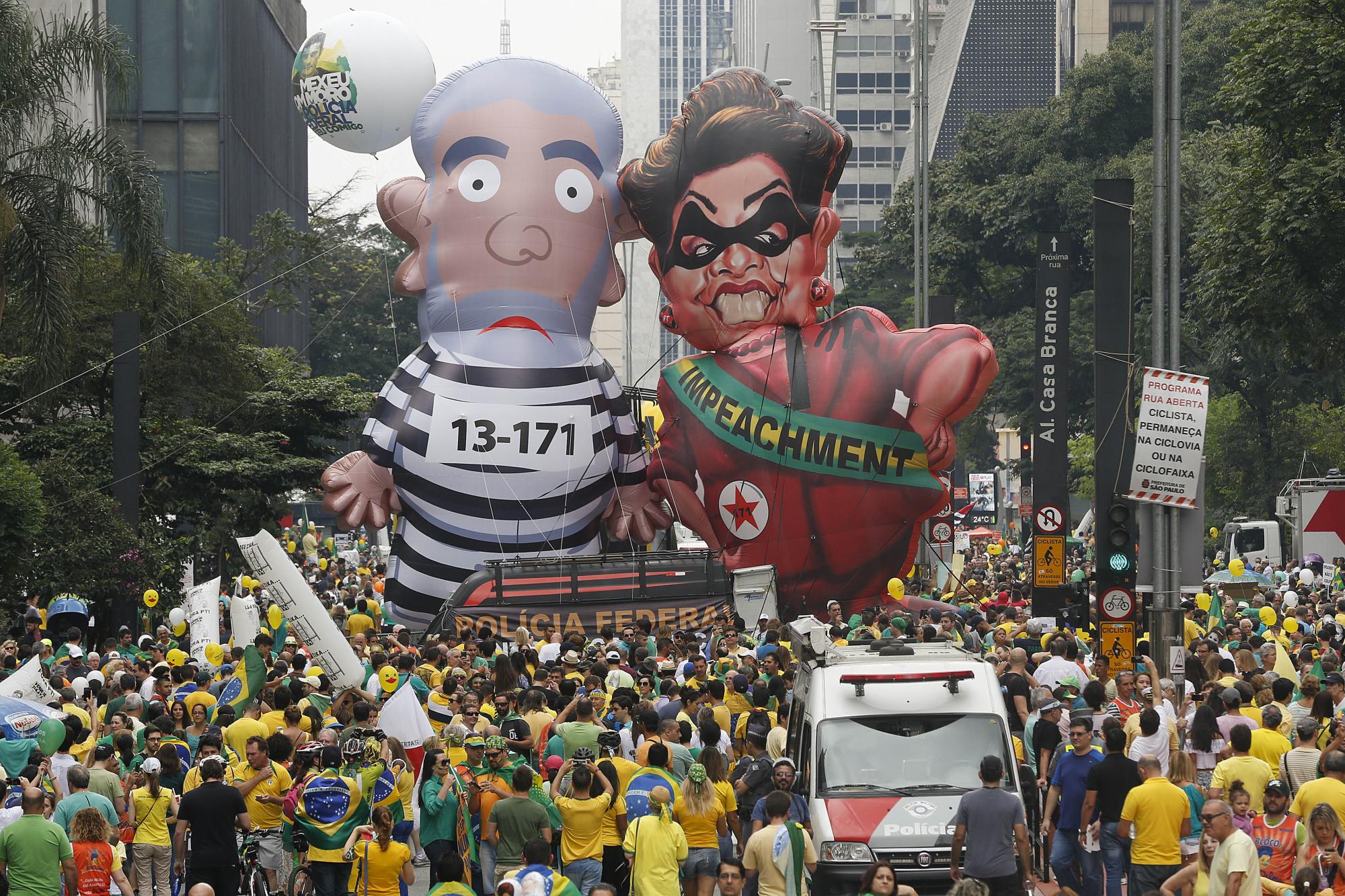 Manifestantes antigubernamentales marchan por Sao Paulo, Brasil, el domingo 13 de marzo de 2016, mientras llevan dos efigies inflables,