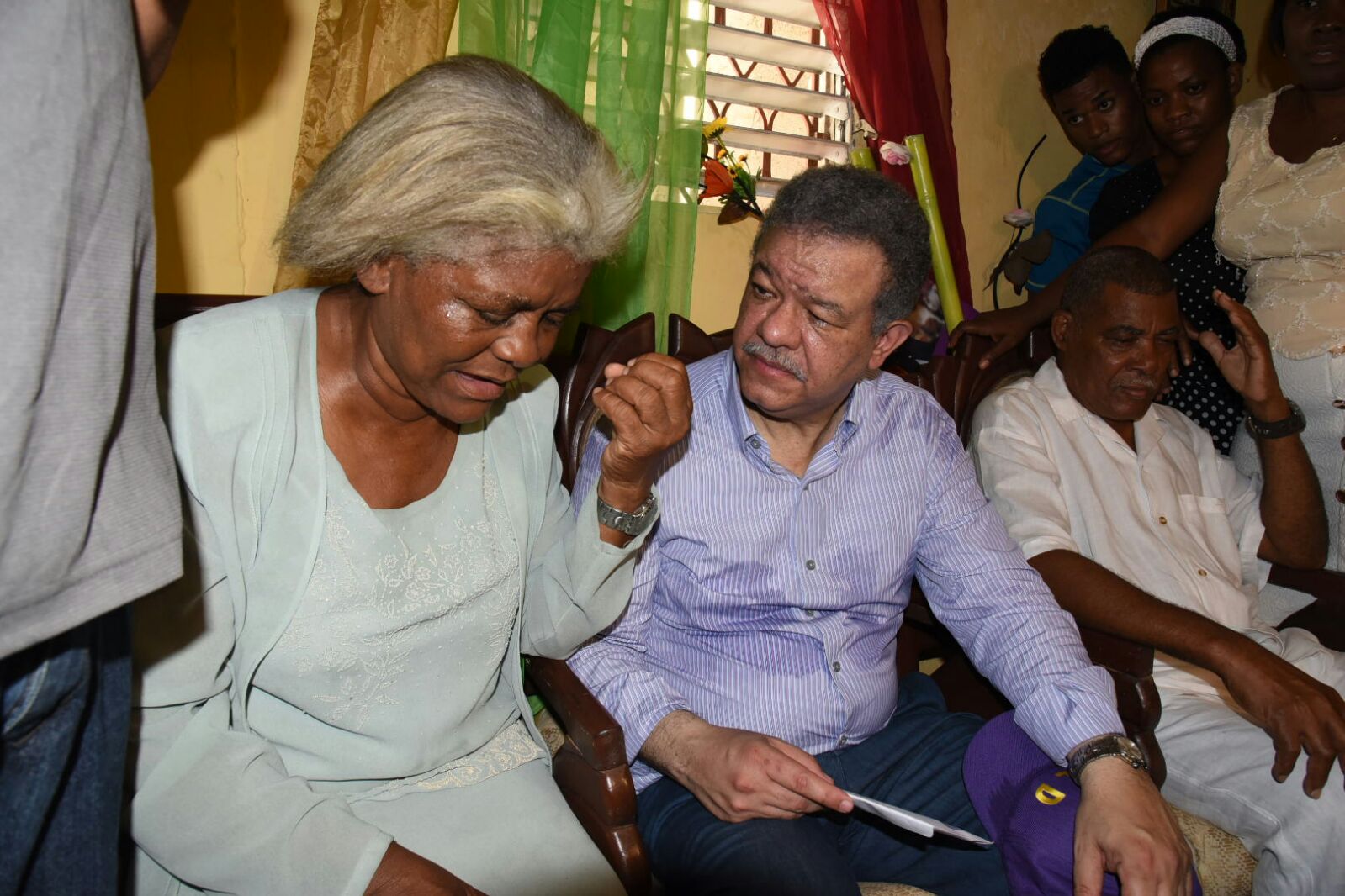 Leonel Fernández (centro) conversa con la esposa de Mario de León (derecha), fundador del PLD en el barrio Las Cañitas. 