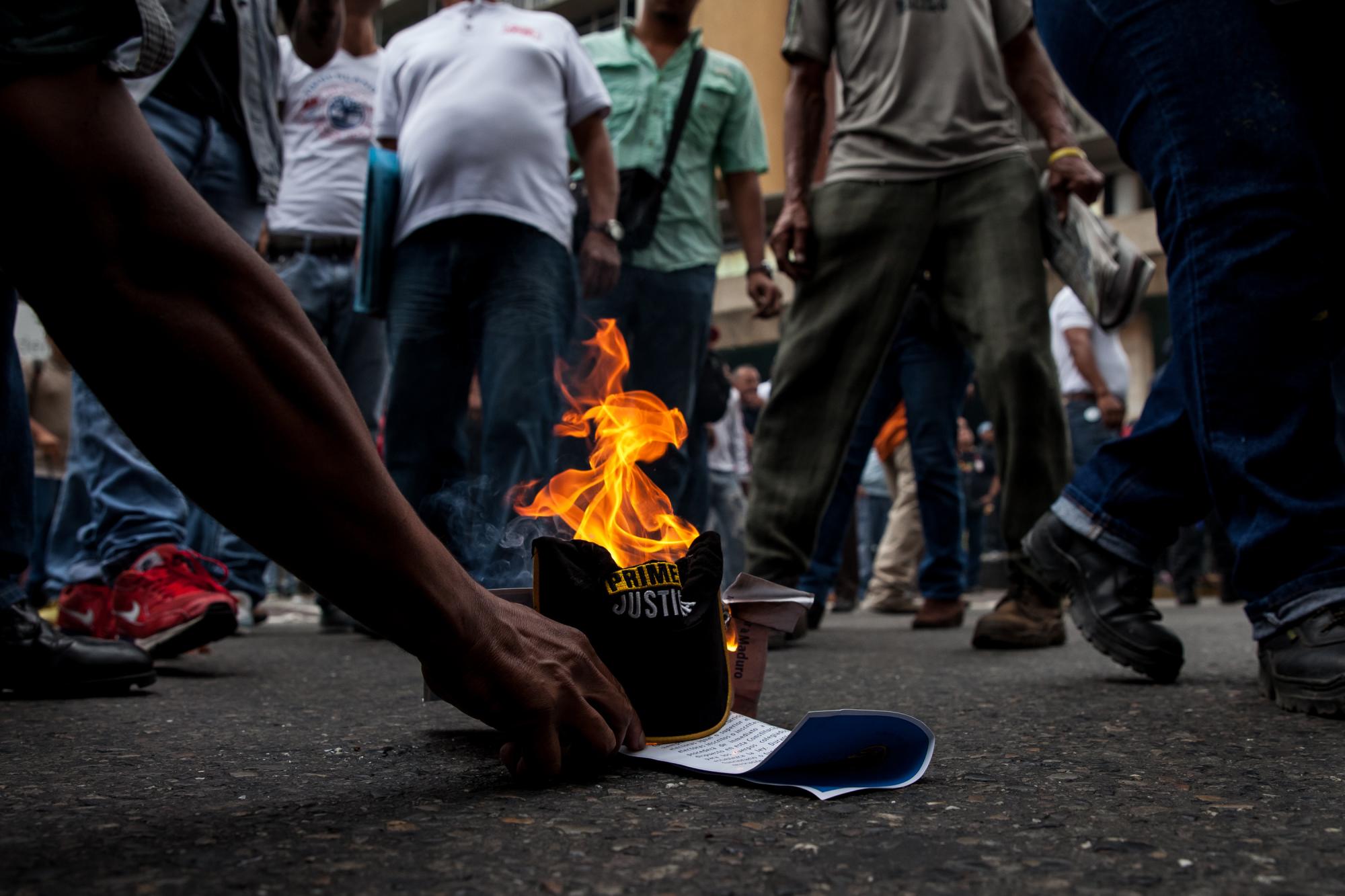 Chavistas queman gorras del partido político Primero Justicia, perteneciente a la coalición opositora durante choques entre ambos grupos de seguidores frente al Consejo Nacional Electoral (CNE) cuando los opositores acudían a la sede del organismo electoral para pedir el documento del referendo revocatorio.