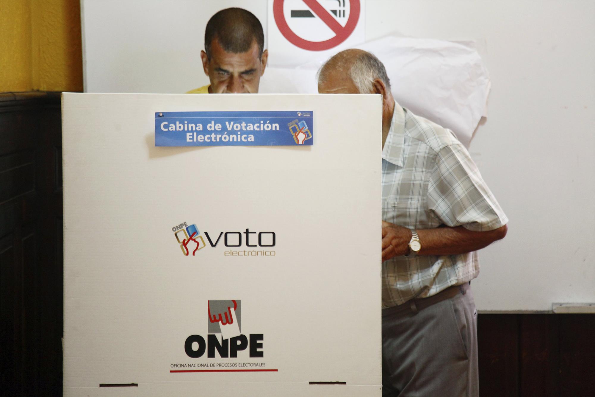 Una persona elige su papeleta en una cabina de votación en los comicios nacionales del Perú.