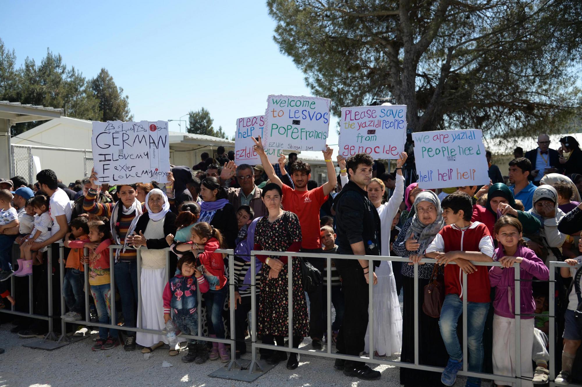 Migrantes y refugiados sostienen pancartas para el papa Francisco. 