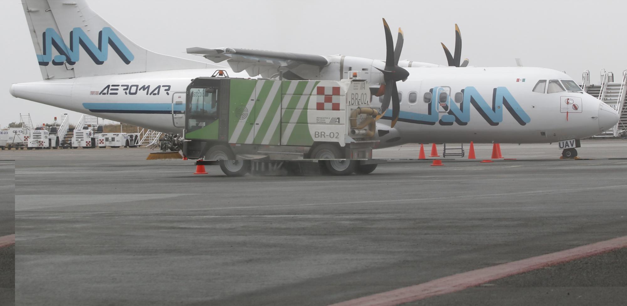Personal de seguridad en el Aeropuerto Internacional de Puebla (AIP) limpia las pistas saturadas de cenizas. 