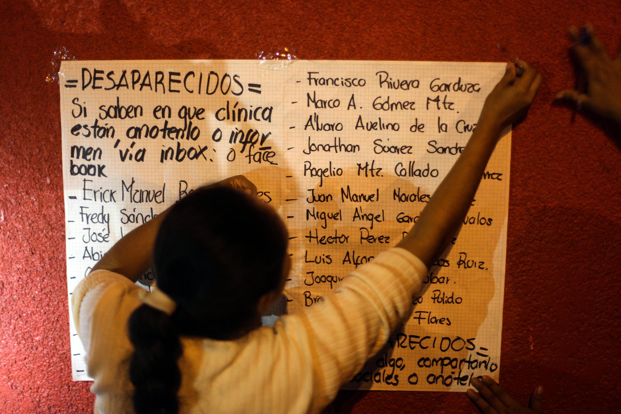 Una mujer coloca una lista de trabajadores desaparecidos fuera de un hospital. 