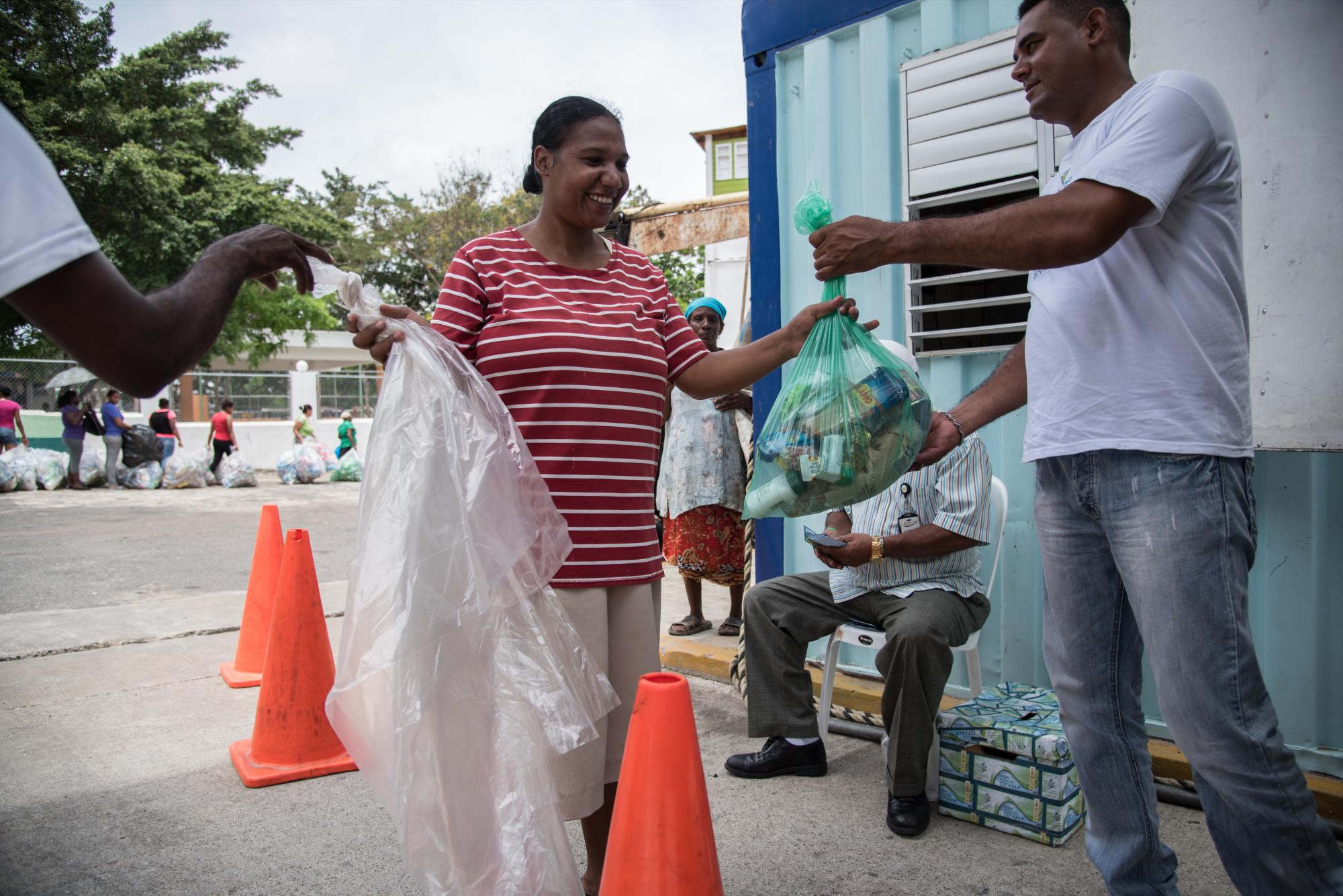 Las personas entregan el ticket y reciben la funda con comida y dos fundas nuevas para recolectar los plásticos.