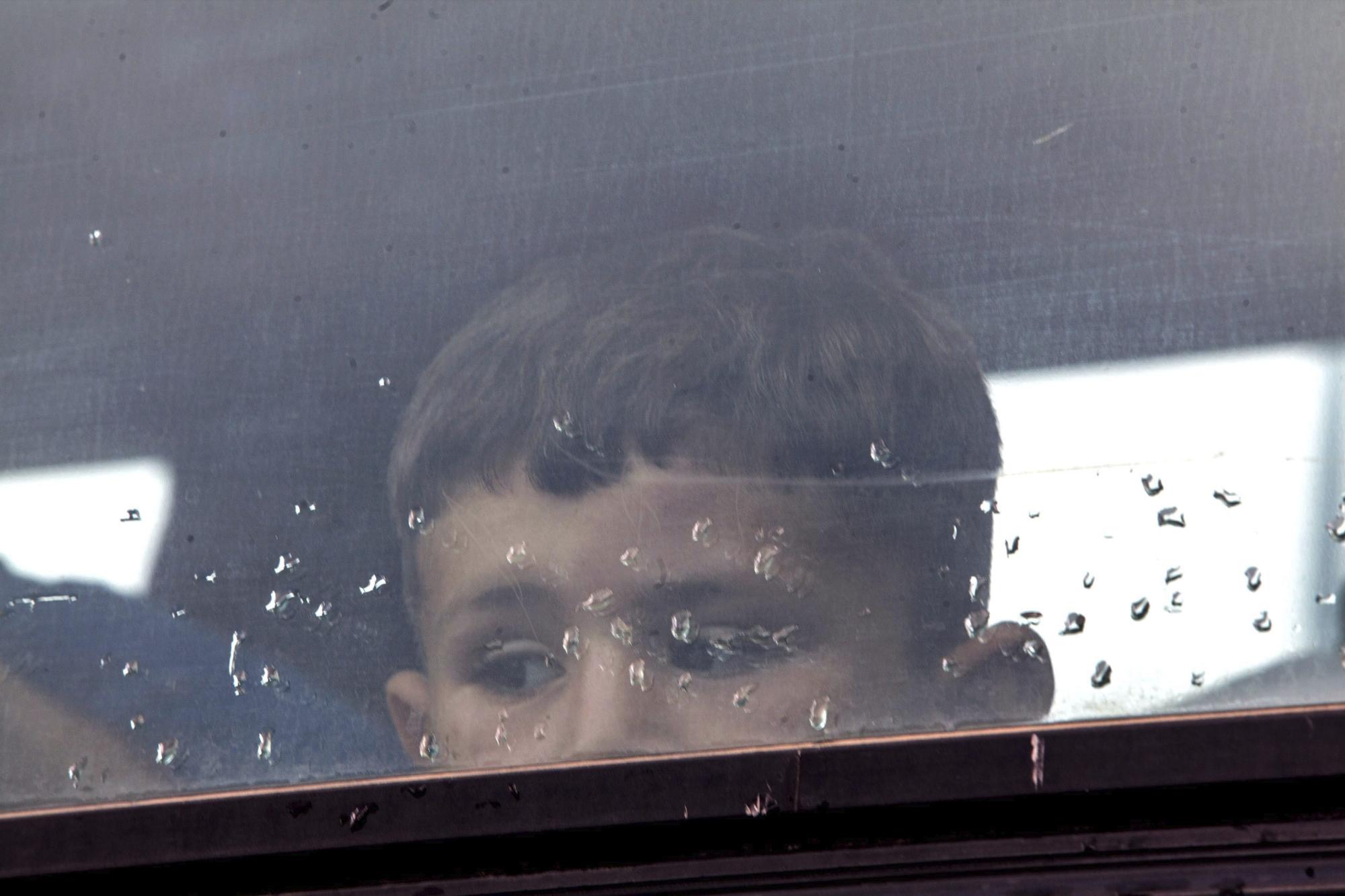 Un niño espera en un autobús a ser trasladado a un centro de acogida mientras la policía griega continúa con el desalojo del campo de refugiados improvisado en la localidad de Polykastro, próxima a Idomeni (Grecia)