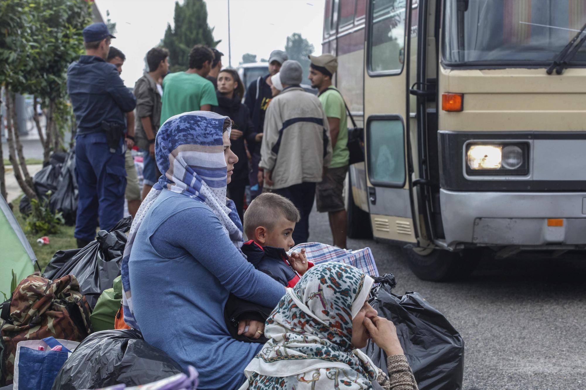 Varios refugiados esperan a ser trasladados a un centro de acogida mientras la policía continúa con el desalojo del campo de refugiados improvisado en la localidad de Polykastro, próxima a Idomeni (Grecia)