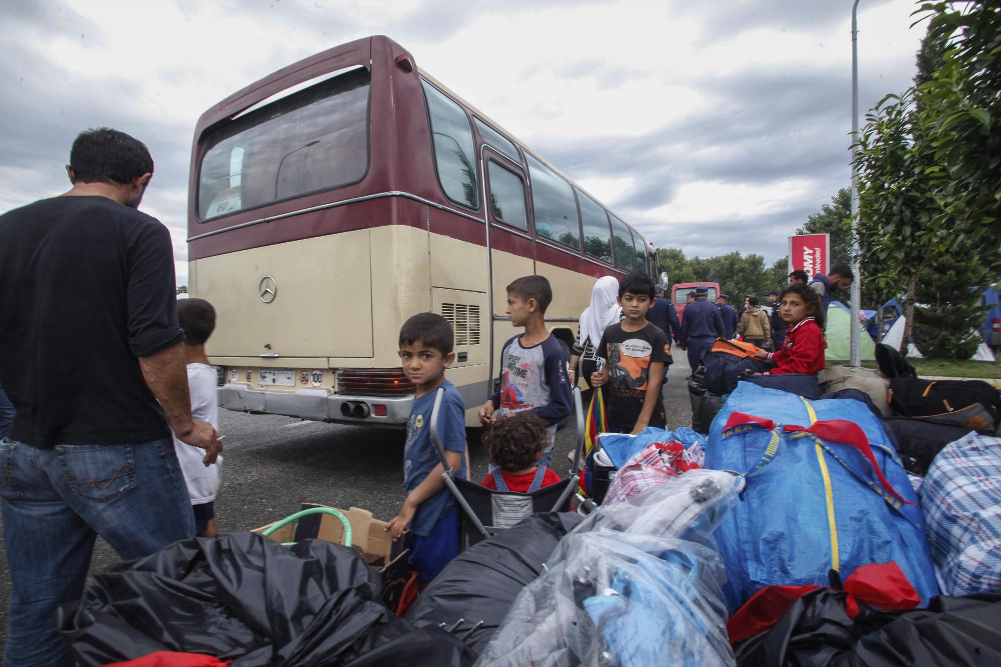 Refugiados e inmigrantes esperan junto a un autobús mientras la policía continúa con el desalojo del campo de refugiados improvisado de la localidad de Polykastro, próxima a Idomeni (Grecia) hoy 13 de junio de 2016. 