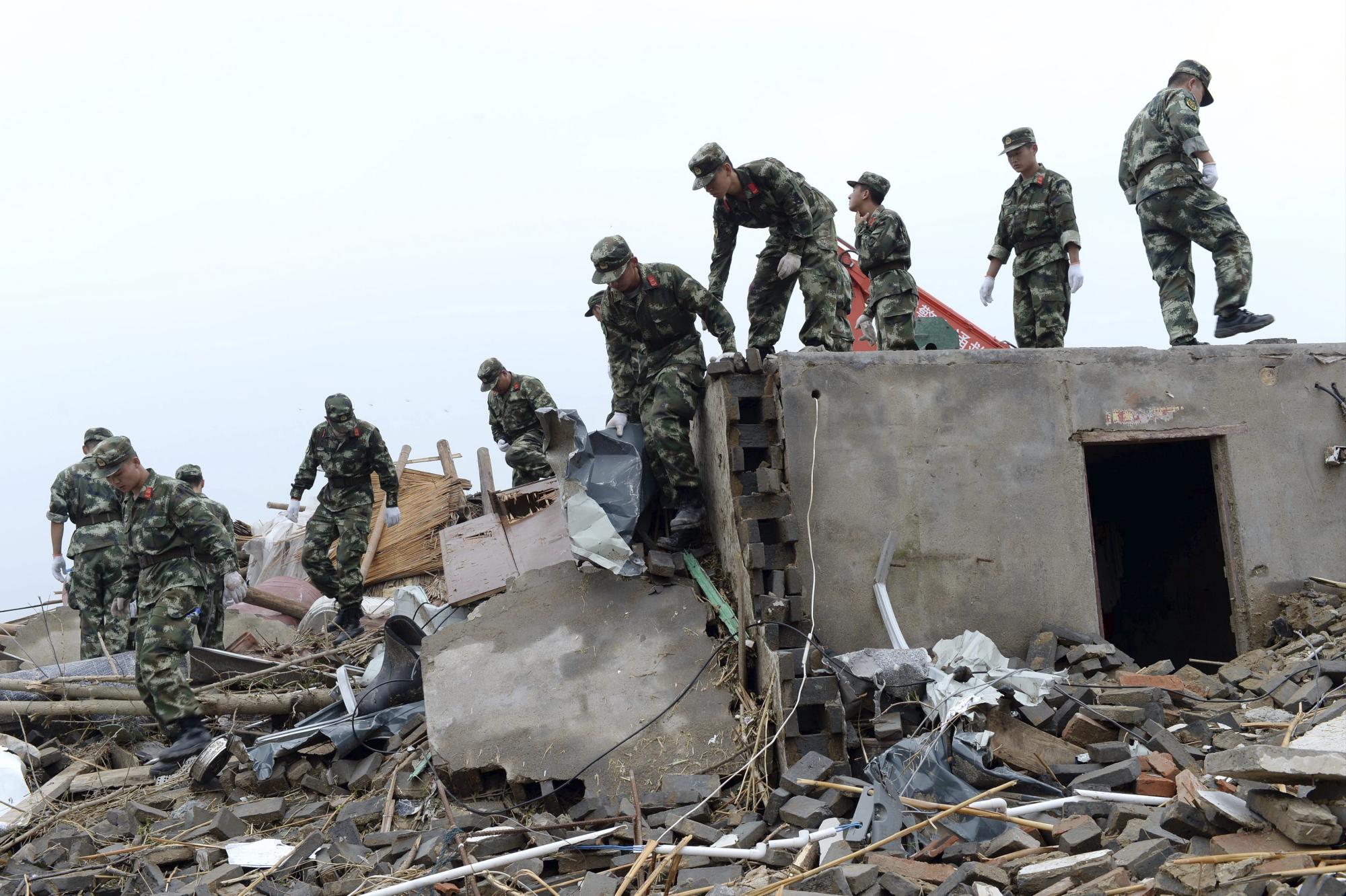 Varios policías caminan entre los escombros de una zona afectada por el tornado en el condado de Funing, provincia de Jiangsu, China.