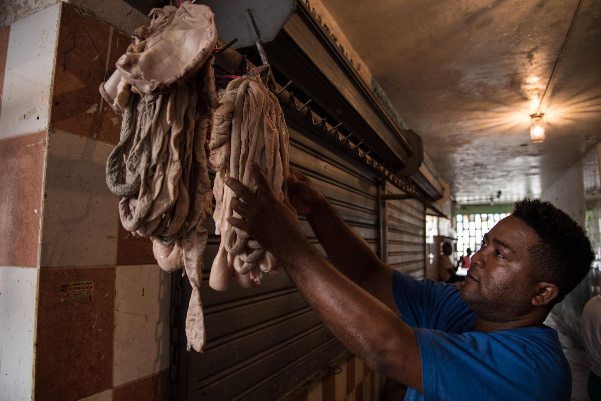 Un carnicero atiende unas carnes.