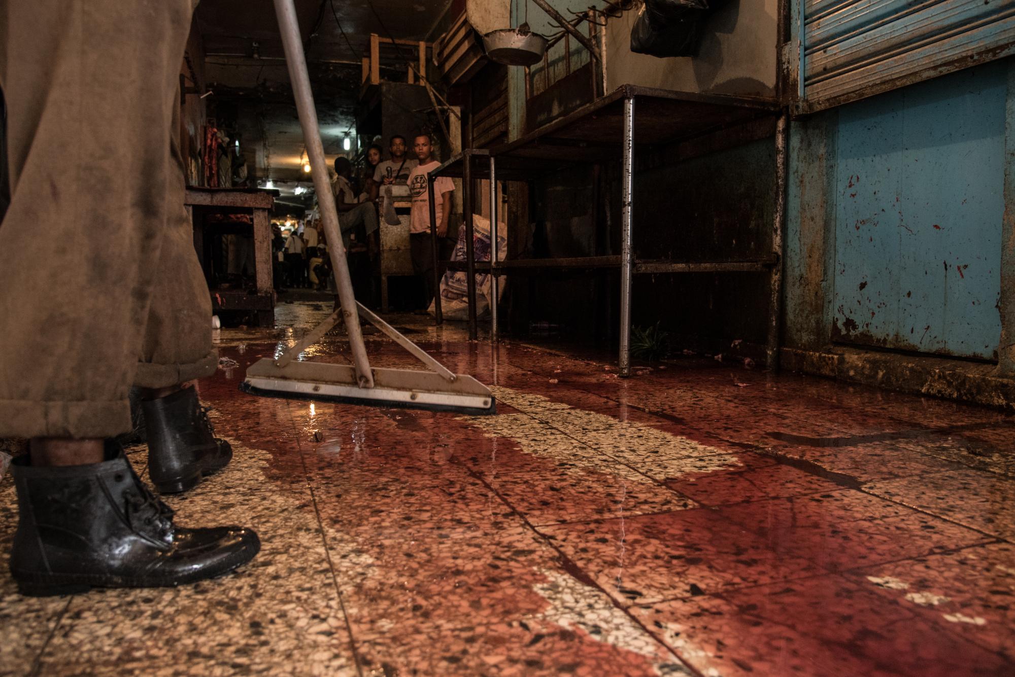 Un carnicero limpia el piso sucio de sangre.