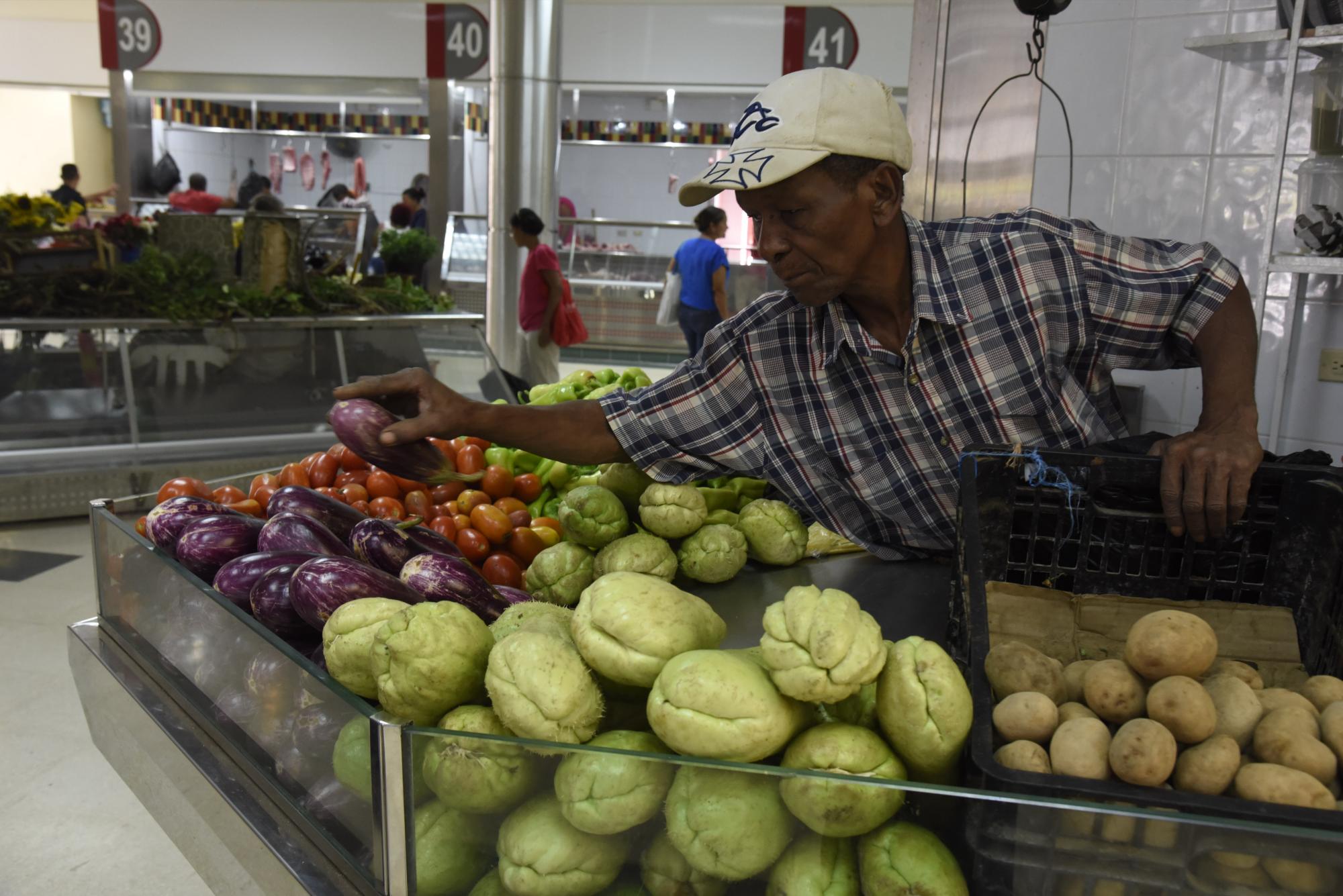Un vendedor organiza sus productos en el mercado de Villas Agrícolas.