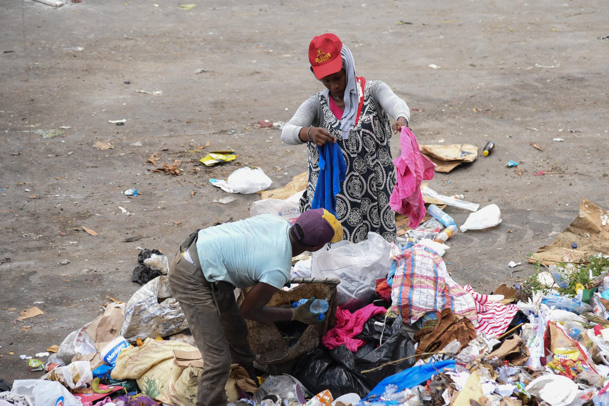 Una mujer “buza” observa una prenda de vestir desechada que encontró entre la basura.