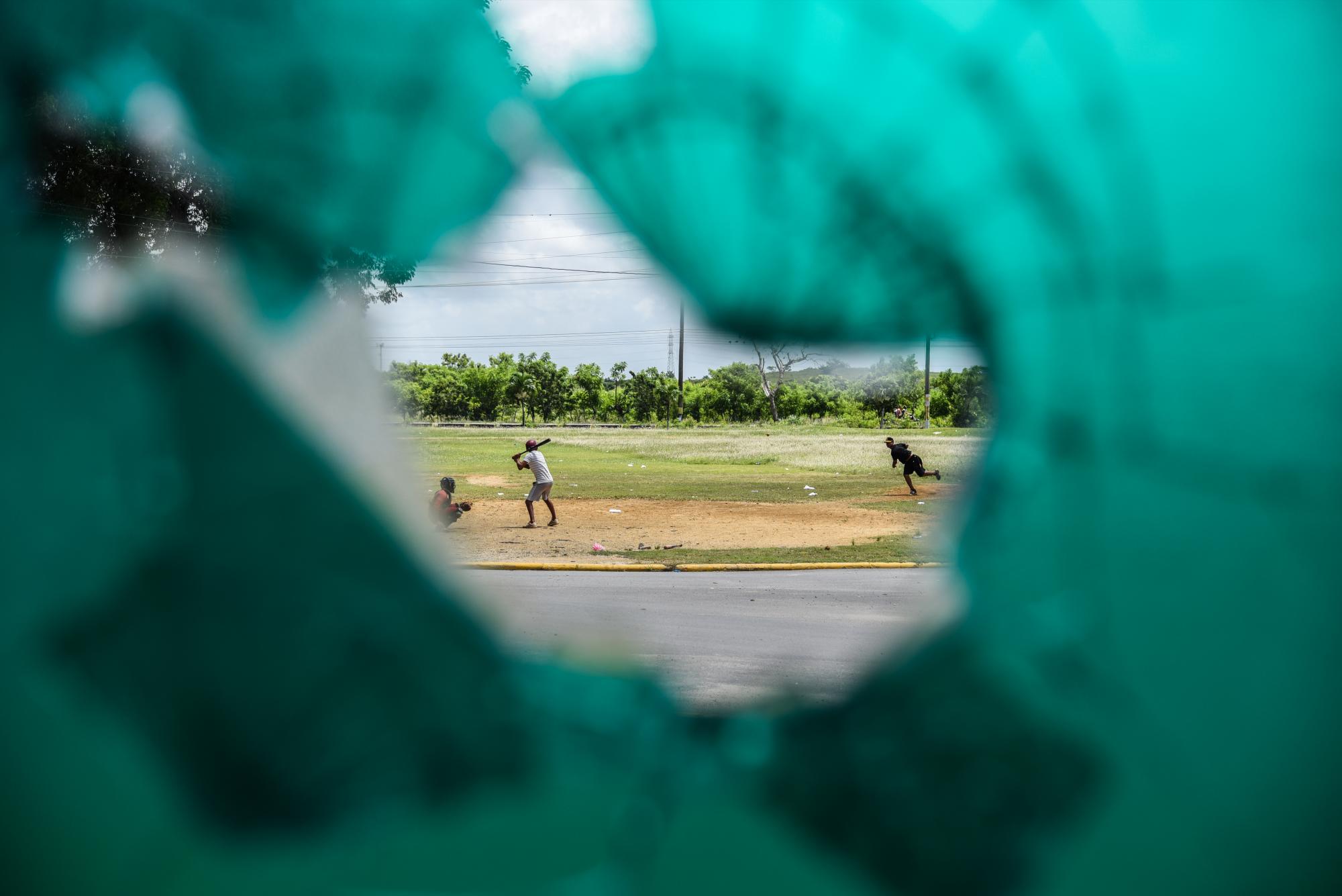 Adolescentes se observan jugando béisbol desde una ventana rota de la iglesia del cementerio.